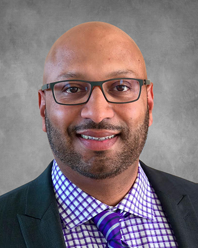 Headshot of Acuity Eye Group co-founder Michael Samuel smiling on a grey background